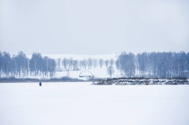 Yalnız bir balıkçı kışın bir gölde balık tutma