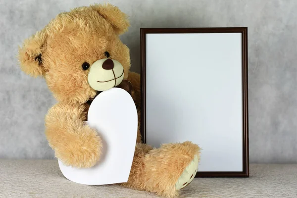 Un orsacchiotto amorevole tiene una cornice con un cuore il giorno di San Valentino — Foto Stock