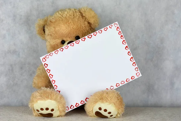 Um urso de pelúcia amoroso mantém uma moldura com um coração no dia do Dia de São Valentim — Fotografia de Stock