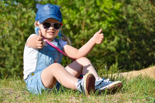 Küçük kız oynamaya ve yeşil çimenlerin üzerine yaz aylarında gülüyor