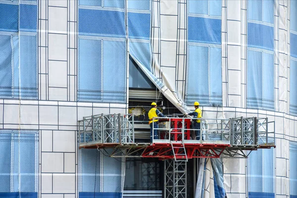 Renkli duvar kağıdı ile kaplı büyük bir binanın duvarında çalışma yüksek irtifa inşaatçılar kaldır