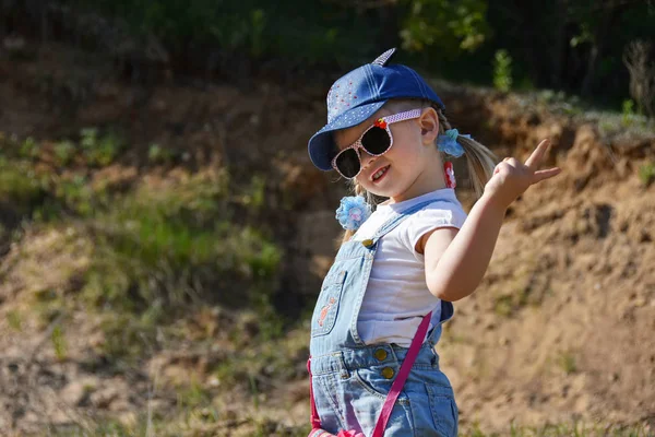 Küçük kız oynamaya ve yeşil çimenlerin üzerine yaz aylarında gülüyor