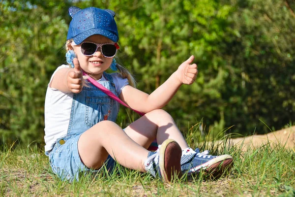 Küçük kız oynamaya ve yeşil çimenlerin üzerine yaz aylarında gülüyor