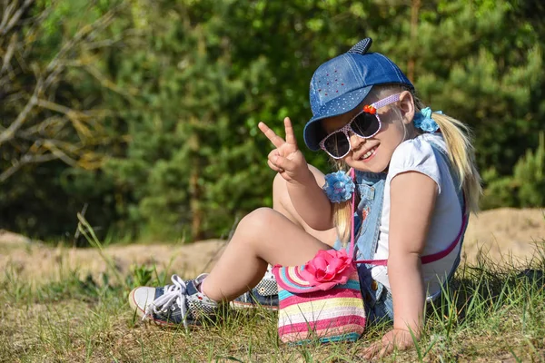 Küçük kız oynamaya ve yeşil çimenlerin üzerine yaz aylarında gülüyor