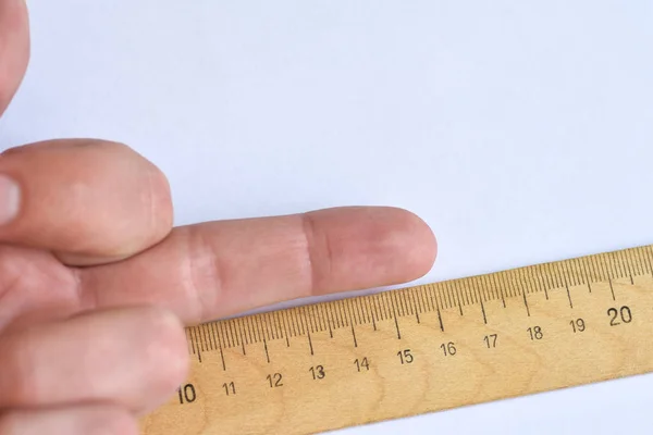 Gesture with fingers of the hand shows the average size male penis with a ruler