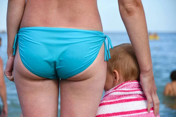 Uma mulher com uma criança está de pé na praia depois de nadar em tempo frio — Fotografia de Stock