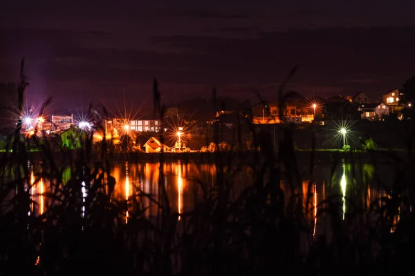 Hüttendorf mit einem See mit hellen Laternen in der Nacht — Stockfoto