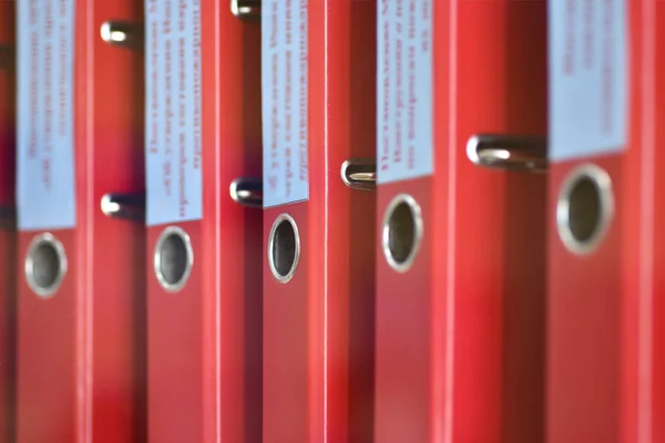 Los archivos rojos de carpetas grandes con inscripciones para almacenar documentos de oficina se colocan verticalmente en un estante —  Fotos de Stock