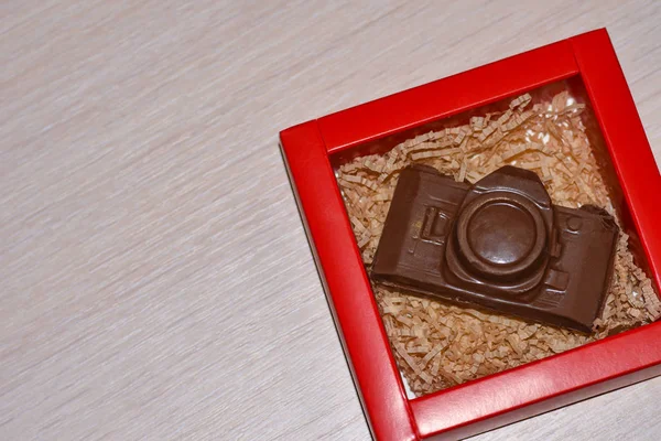 Câmera de chocolate de presente de ano novo em uma caixa vermelha na mesa, copie-cole — Fotografia de Stock