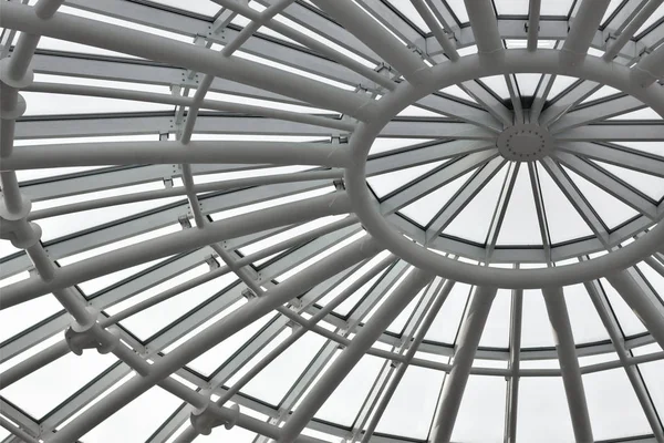 Round white metal frame of the glass roof of the building, bottom view