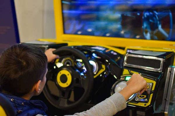 Teenager plays on the gaming machine simulator car in the club