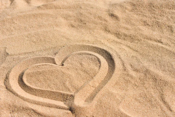 Hand drawn heart on sea sand on the beach