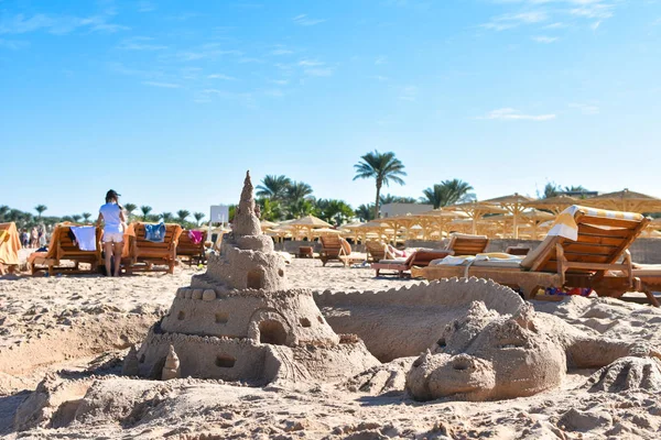 A figura de um dragão e um castelo de areia na praia à tarde — Fotografia de Stock