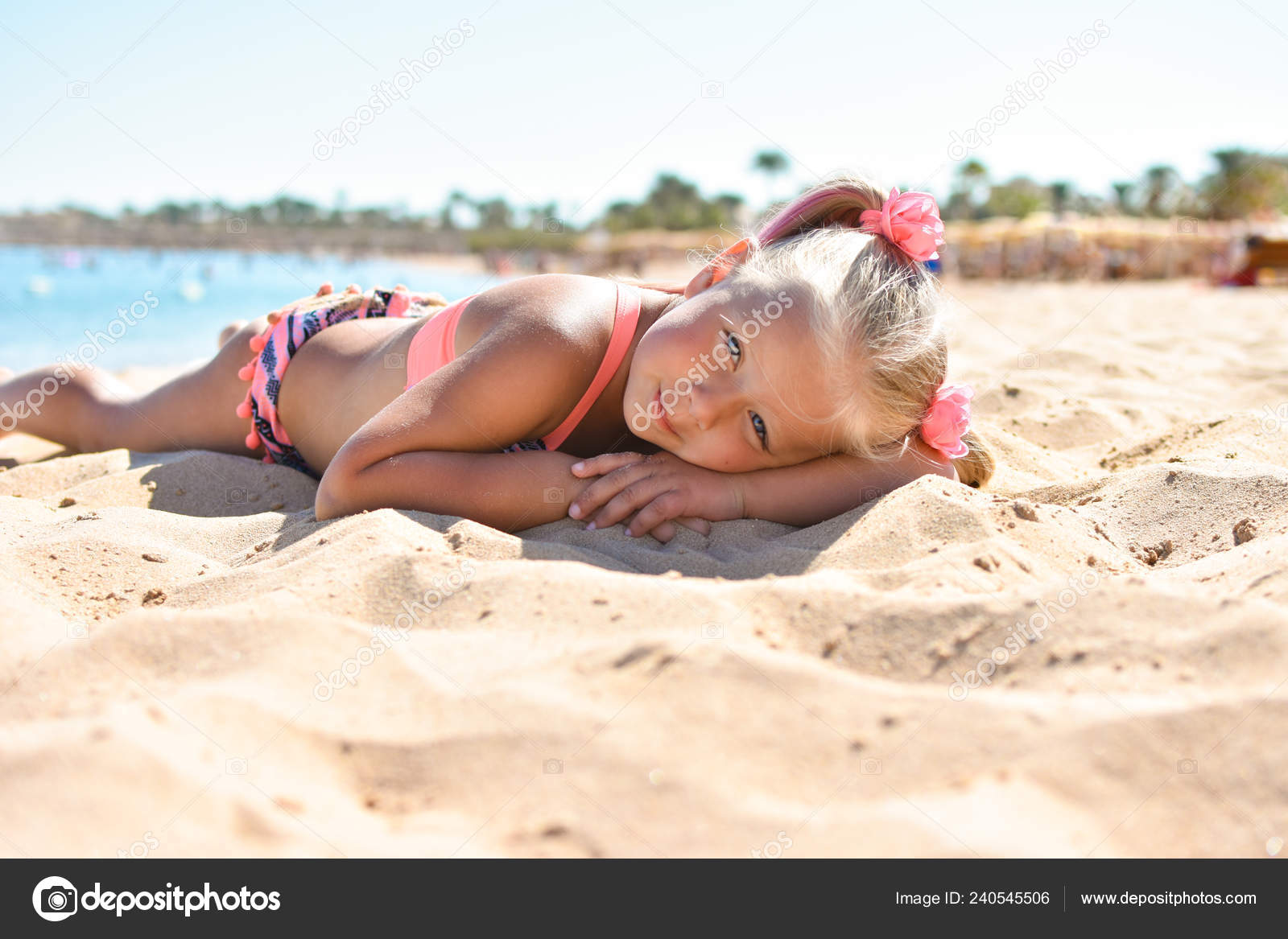 The girl lies on the beach sand near the sea and sunbathes Stock Photo