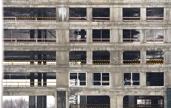 Workers install double-glazed windows in a building under construction