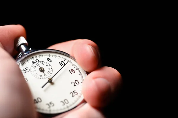 Male hand starts the analog stopwatch on a black background, close-up, isolate, copy space — Stock Photo, Image