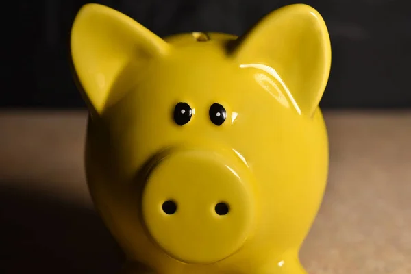 Yellow pig moneybox without coins on a black background