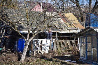 Bir adam Belarus kıştan sonra bahar bir ahır çatısı onarır