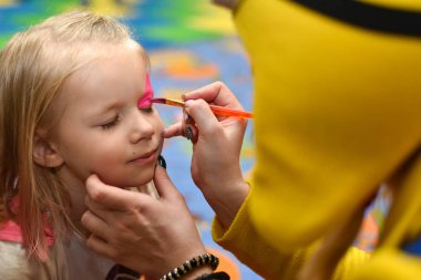 Animator bir tatil üzerinde küçük bir kız boya yüzünü boyar