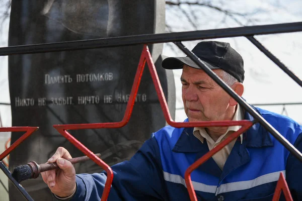 A man paints the fence on the monument to the dead Soviet soldiers in the second world war.