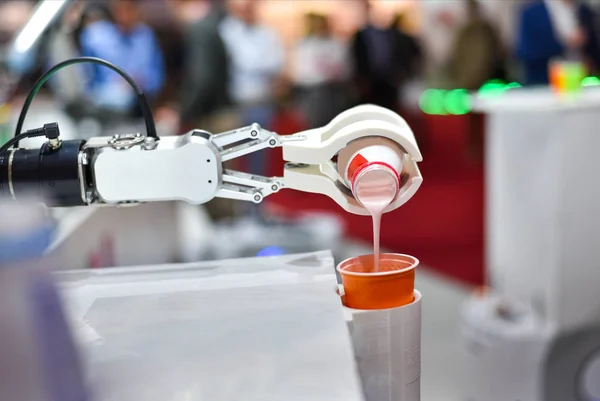 Yapay zekaya sahip mekanik bir robot plastik bir bardağa kokteyl döküyor.