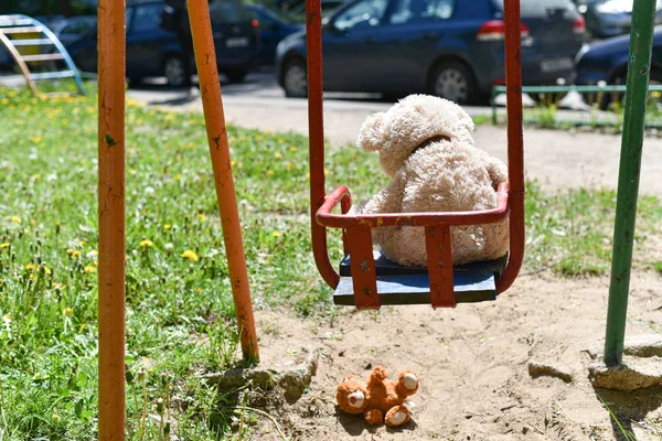 Gevaar van vallende kind, teddybeer viel op de grond van een oude schommel — Stockfoto