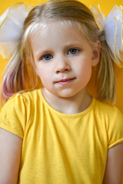 Portrét malé holčičky ve žlutých šatech na žlutém pozadí — Stock fotografie