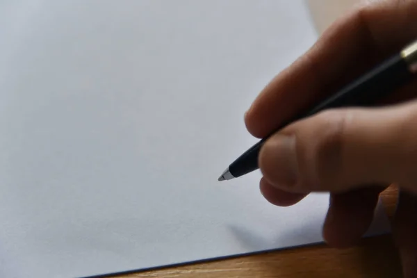Penna i hand på vitt papper på bordet i kontoret — Stockfoto
