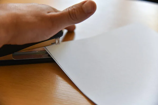 Hand staples paper on office desk — Stock Photo, Image