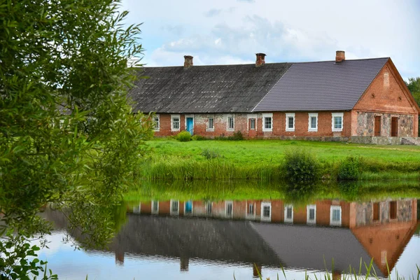 Gammal röd tegelbyggnad återspeglas i vatten — Stockfoto