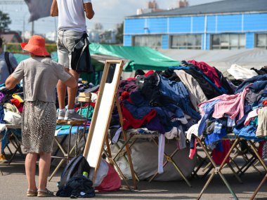Woman measures clothes at second hand market