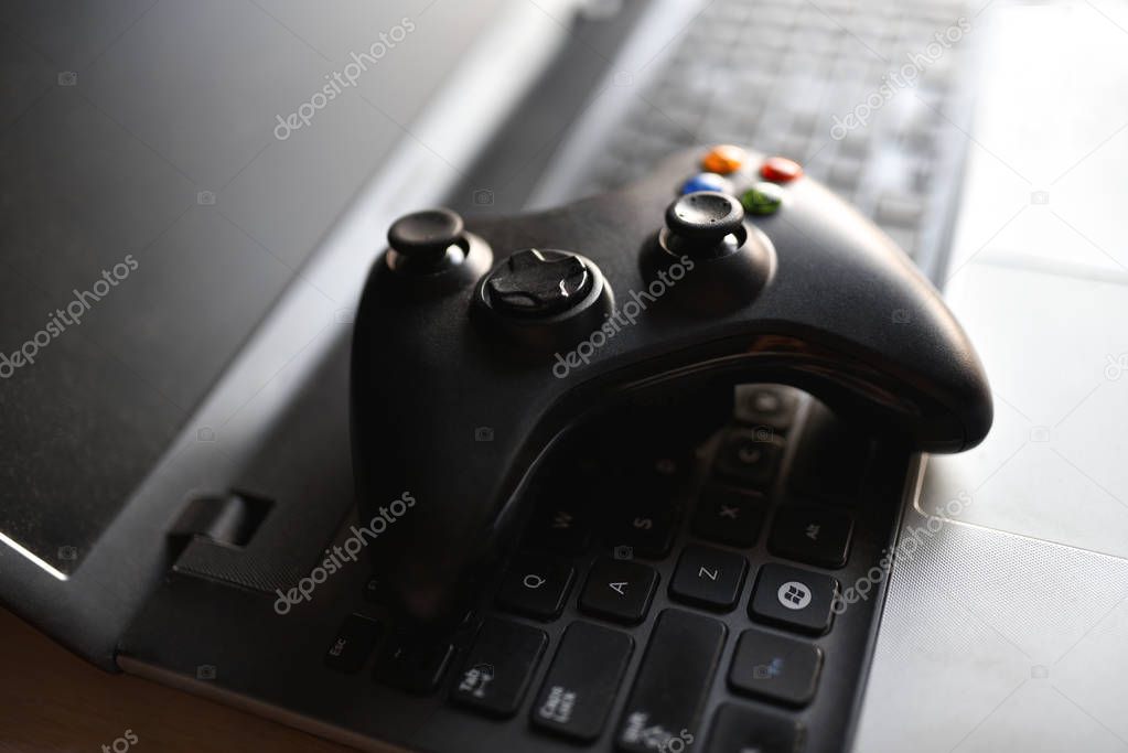 Game joystick lies on a black laptop