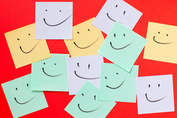 Smilies on paper for notes. Isolated on red background.