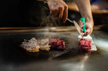 Bir Japon restoranında teppan gösterisi, müşterinin önünde doğrudan yemek pişirmek, balık, pirinç, et, sebze