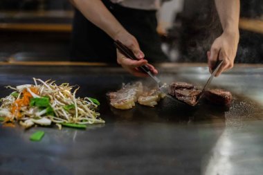 Bir Japon restoranında teppan gösterisi, müşterinin önünde doğrudan yemek pişirmek, balık, pirinç, et, sebze