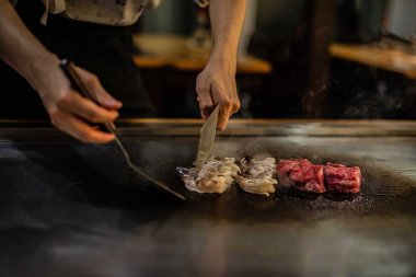 Bir Japon restoranında teppan gösterisi, müşterinin önünde doğrudan yemek pişirmek, balık, pirinç, et, sebze