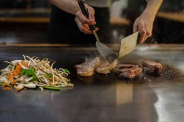 Bir Japon restoranında teppan gösterisi, müşterinin önünde doğrudan yemek pişirmek, balık, pirinç, et, sebze