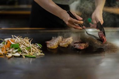 Bir Japon restoranında teppan gösterisi, müşterinin önünde doğrudan yemek pişirmek, balık, pirinç, et, sebze