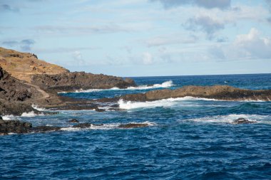 Tenerife İspanya 'sında deniz köpüğü ve Atlantik Okyanusu dalgaları kayalara çarpıyor. Ufkun üzerinde desenli bulutlarla gökyüzü