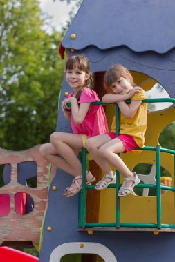Oyuncak evin balkonunda oturan iki kız kardeş. Mutlu yaz zamanları.