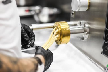 Profesyonel bir makineyle taze makarna yapma süreci.