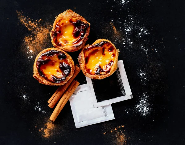 Geleneksel Portekiz tatlısının üst görüntüsü - Tarçınlı Pastel de nata ve siyah arkaplanda şeker