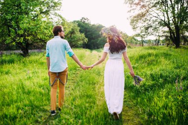 Romantik kavramı. Genç çift bir çayır yürüyüş elele.
