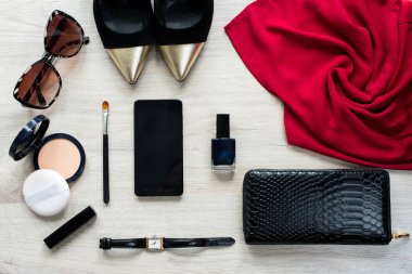 Üstten görünüm için kadın kadın moda aksesuar. Kırmızı giydirin, güneş gözlüğü, yüz pudrası, yapmak fırça, tırnak cilası, saat, cep telefonu, ruj, altın sivri ayakkabılar, siyah deri çanta.