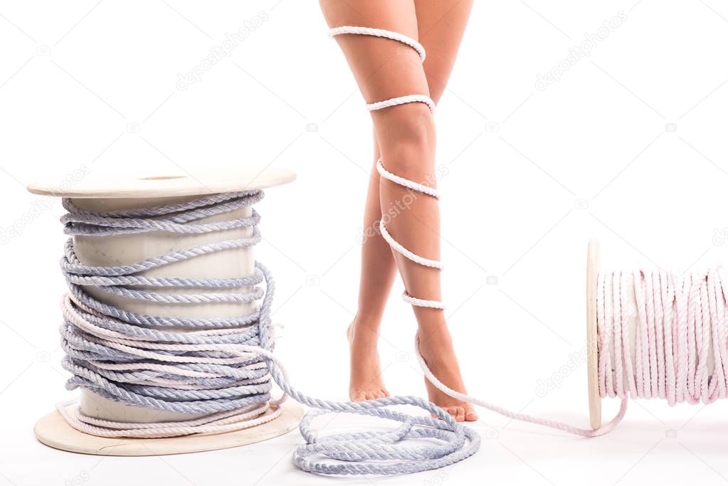 Legs pain concept - legs tied with rope isolated on white. Female naked sexy legs wrapped, copyspace.