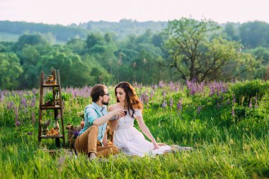 Genç bir çift gözlük açık bir sessiz piknik kırmızı şarap ile tıklatması