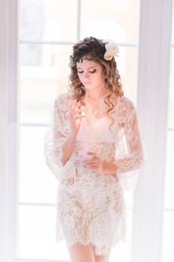 Dantelli sabahlığı içinde yanan bir mum tutan genç gelin