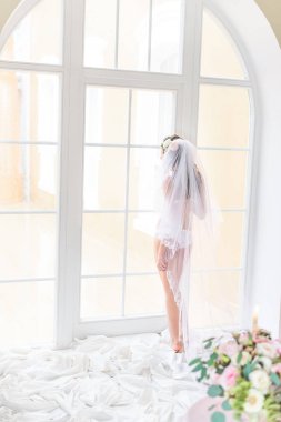 Gelin peçe ile kapalı geri bir dantelli beyaz iç çamaşırı hafif bir pencere yakınında duran
