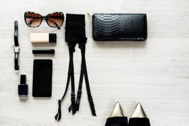 Üstten görünüm için kadın kadın moda aksesuar. Siyah jartiyer kemer, güneş gözlüğü, yüz pudrası, tırnak cilası, saat, cep telefonu, ruj, altın sivri ayakkabı, çanta. Metin alanı olan tablo
