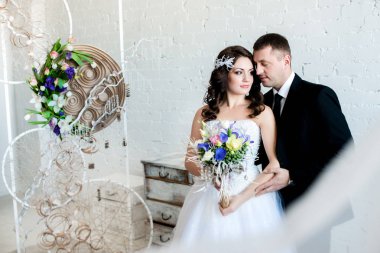 Damat gelini bir buket ışıklı bir güzel oda tutarak, kucaklayan